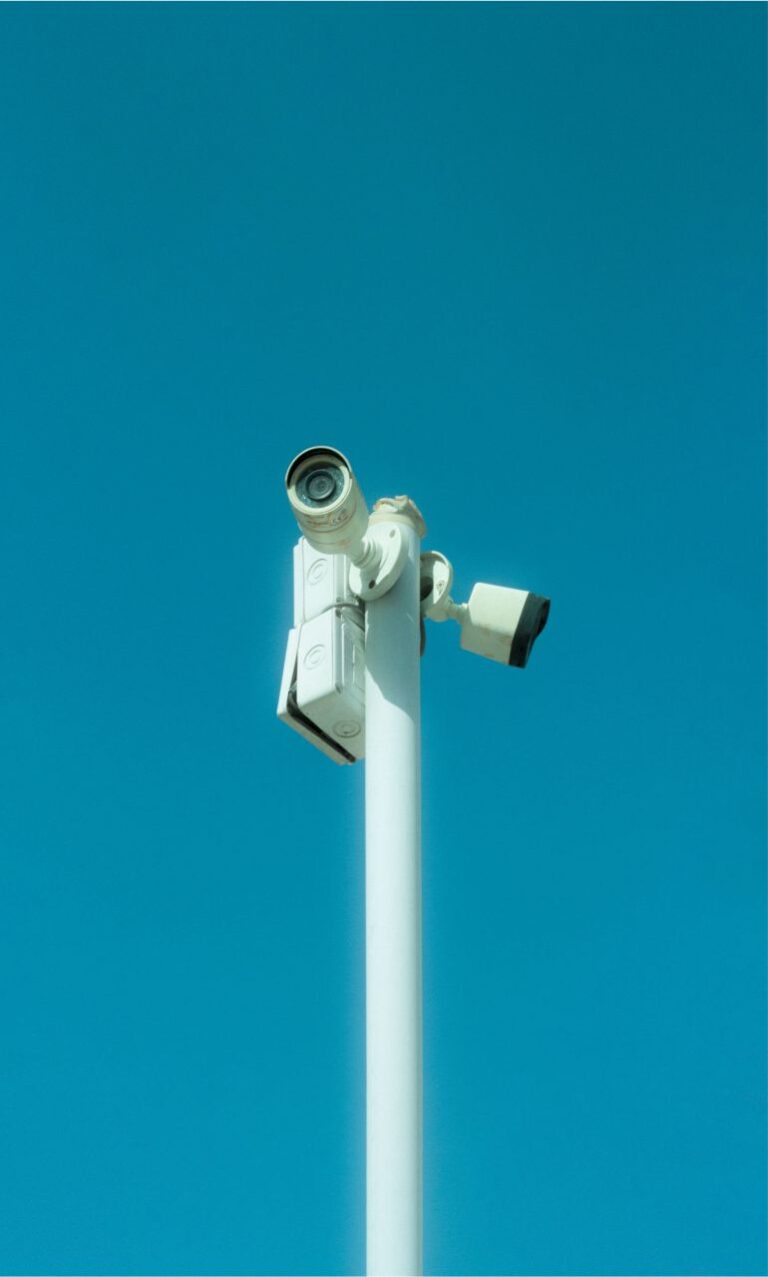 Due telecamere di videosorveglianza su palo bianco contro il cielo